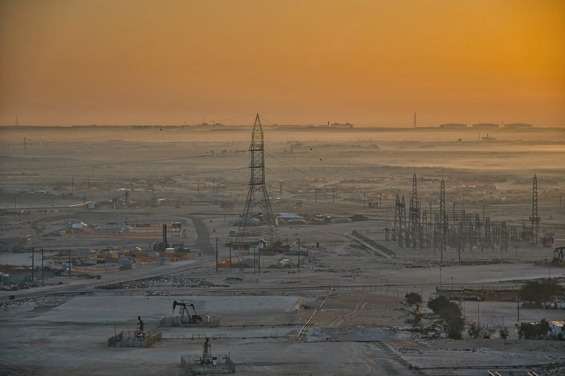 Pumpjacks and power lines across a field at hazy dawn