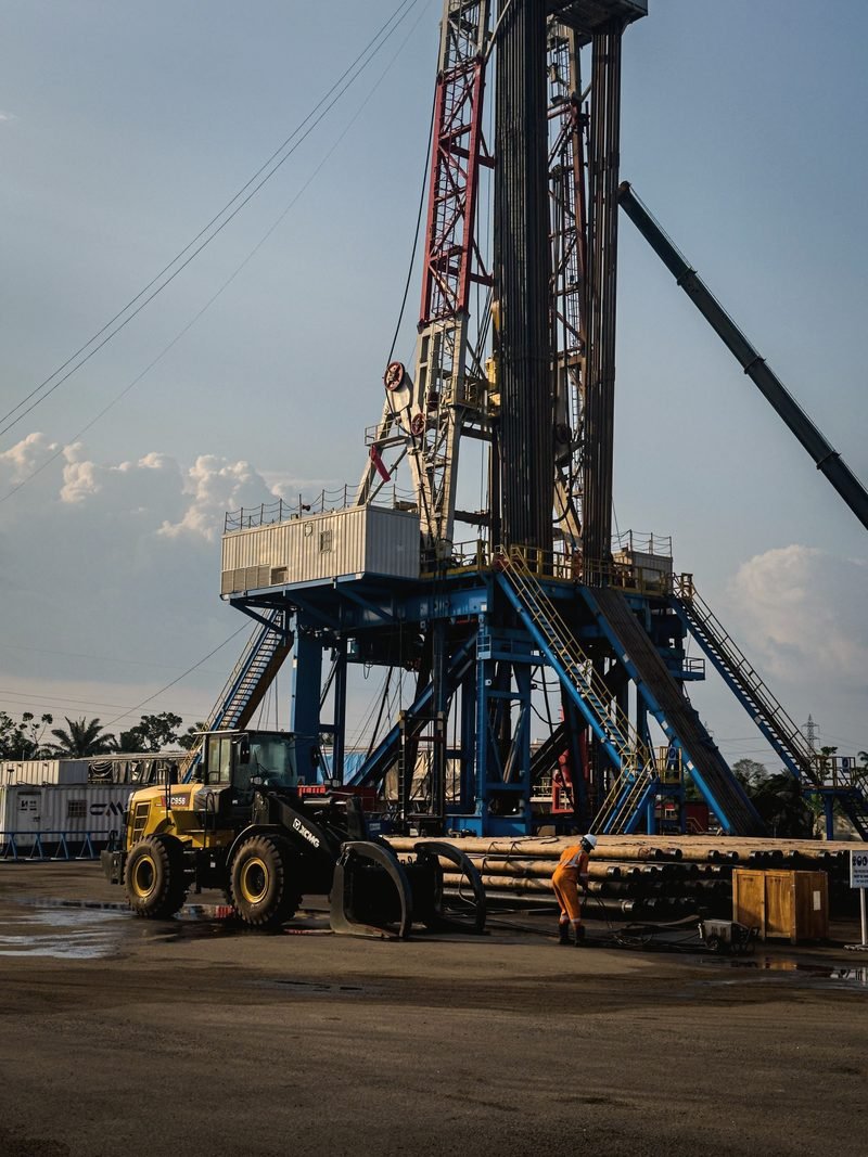 A land rig with blue substructure, a loader and pipe in the yard in front