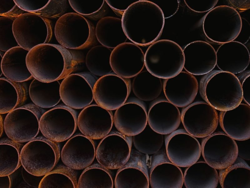 Rusted pipe ends stacked in rows, seen end-on