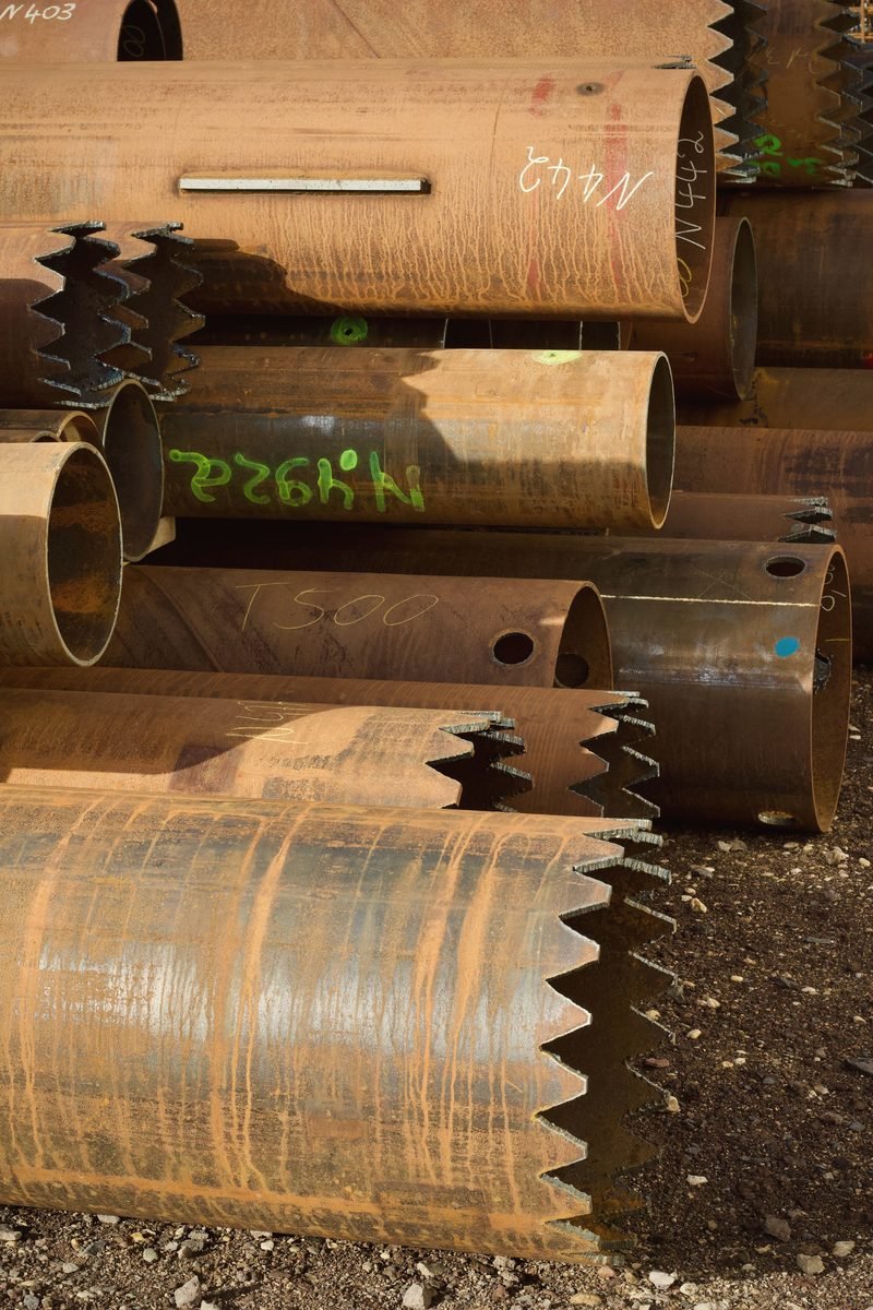 Large rusted steel pipe stacked on blocks