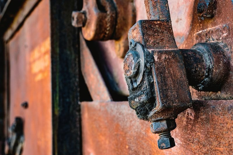 Close-up of a rusted bolt and bracket on orange steel